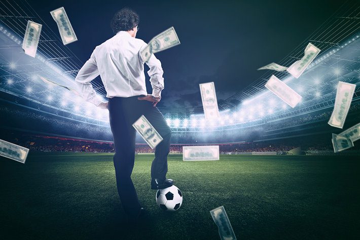 Man standing on football field with money flying